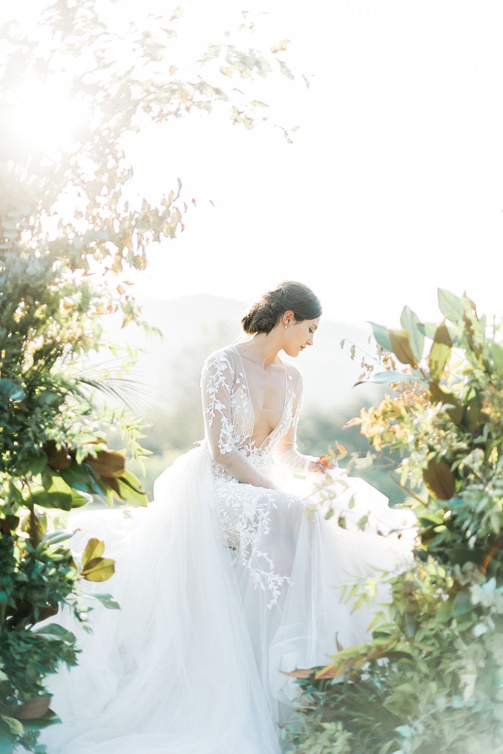 fine art portrait of bride sitting on a floral arch